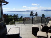 Topless glass Infinity railing with black powder coated posts protects the view of Guemes channel on this Anacortes, WA deck.